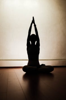 Serene silhouette of a woman performing yoga in a peaceful indoor setting.